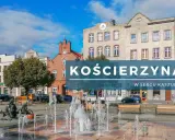 Kościerzyna rynek z fontanną i ławkami, otoczony kamienicami.
