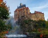Zamek na skale nad wodospadem, jesienne liście i mgła tworzą malowniczy krajobraz. Wspaniałe wschodnie Niemcy atrakcje.