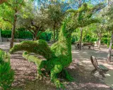 Un dragón de topiaria verde en un parque. Un lugar genial donde ver animales en Madrid, aunque este sea de plantas.