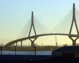 El imponente puente de Cádiz se alza sobre el agua, con sus cables tensos y pilares icónicos contra un cielo despejado.