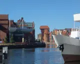 Widok na Motławę w Gdańsku. Na pierwszym planie biały dziób statku, w tle zabytkowe kamieniczki i Żuraw. Gdańsk starówka zachwyca.