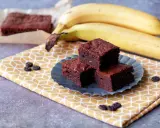 Saftige bananen brownies auf einem gelben Tuch, daneben reife Bananen.