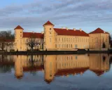 Das Schloss Rheinsberg spiegelt sich im Wasser. Die historische Altstadt von Rheinsberg zeigt sich von ihrer schönsten Seite.