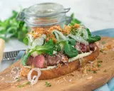 En läcker steak sandwich med saftigt kött, krispig sallad, lök och riven ost på rostat bröd.
