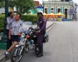 Trzy policjantki w mundurach stoją obok motocykla policyjnego na ulicy w Hawanie.