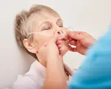 Ältere Frau mit Nasenbrille zur Sauerstofftherapie, ein Zeichen des COPD-Krankheitsbildes.