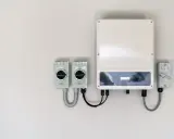 En vit vägg med en solcells-växelriktare och tre D.C. isolatorer. En del av systemet för att omvandla solenergi till el.