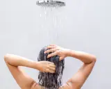 Frau wäscht sich die Haare unter der Dusche, eine natürliche Methode, um die Haare ohne Shampoo zu reinigen.