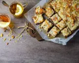 En skiva vegansk morotskaka med glasyr och nötter, serverad med två koppar te med citron.