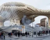 Ein Meisterwerk des Dekonstruktivismus: die Metropol Parasol in Sevilla. Menschen schlendern unter der organisch geformten Holzkonstruktion hindurch.