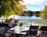 Gedeckter Tisch mit Blick auf einen See und Herbstlaub.