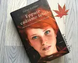 Copertina del libro "Eppure cadiamo felici" di Enrico Galiano, con il volto di una ragazza dai capelli rossi e occhi azzurri. Una foglia d'acero rossa completa la scena.