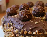 Pyszny tort ferrero rocher, obficie udekorowany czekoladowymi kulkami i posypany orzechami.