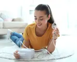 Junge Frau mit Inhalator. Sie hält die Maske und fragt sich, wie inhaliert man richtig durch Mund oder Nase.