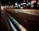 Torowisko tramwajowe w nocy, światła miasta rozmyte, jakby w ślepocie zmierzchowej.