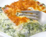 Deliciosa lasaña de espinacas cremosa, gratinada y lista para disfrutar. Un tenedor se hunde en esta maravilla.