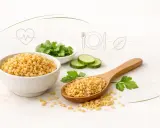 Kasza bulgur w misce i na łyżce, obok plasterki ogórka i zielenina. Czy kasza bulgur jest zdrowa? Tak, to bogactwo błonnika i witamin.