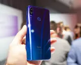 Błyszczący, niebieski tył telefonu Redmi 7 Pro z podwójnym aparatem 48MP i czytnikiem linii papilarnych, trzymany w dłoni.