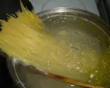 Długi makaron spaghetti zanurza się w gotującej wodzie. Czas, ile gotuje się makaron, zależy od jego grubości.