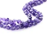 Tre fili di sfaccettate pietre viola, il cui nome è ametista, su sfondo bianco.