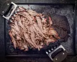Zartes pulled beef, frisch aus dem Dutch Oven, wird mit Fleischkrallen zerteilt. Perfekt für BBQ!
