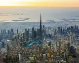 Luftaufnahme von Dubai bei Sonnenuntergang. Der Burj Khalifa ragt empor, umgeben von Wolkenkratzern und den künstlichen Inseln. Ein Blick auf die Dubai Besonderheiten.