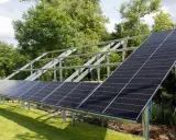 Instalacja fotowoltaiki na gruncie w ogrodzie. Panele słoneczne montowane na metalowej konstrukcji, gotowe do produkcji czystej energii.