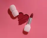 Un cuore di rossetto rosso, con un rossetto e un applicatore, mostra diversi tipi di rossetto.