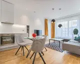 Nowoczesny salon z aneksem kuchennym. Opis pokoju po angielsku: kuchnia z piekarnikiem, szklany stół z krzesłami, sofa, stolik kawowy, dywan.