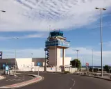 Kontrollturm am Almeria Airport mit Parkplatzschildern und Straßenbeleuchtung unter blauem Himmel.