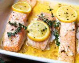 Saftiger Lachs mit Kartoffeln im Ofen, garniert mit Zitronenscheiben und frischem Thymian.