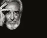 Ritratto in bianco e nero di un uomo anziano con barba bianca, mano sulla fronte. Un fotografo napoletano famoso cattura uno sguardo intenso.
