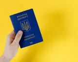 Dłoń trzyma niebieski paszport Ukrainy. Ważność dokumentu jest kluczowa dla statusu ukr do kiedy.