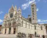 Il Duomo di Siena, con la sua imponente torre campanaria a strisce, è un must per chi cerca cosa visitare a Siena. La piazza antistante è animata da bancarelle.