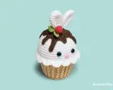 Adorable cupcake amigurumi con orejas de conejo, glaseado blanco, chispas de chocolate y una cereza. ¡Un dulce amigo tejido!