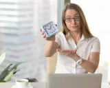 Kobieta z zegarkiem w dłoni pokazuje, że czas na zadaniowy czas pracy minął.