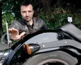 Mężczyzna pokazuje mocowanie tablicy rejestracyjnej motocykl, omawiając przepisy.