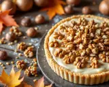 Une délicieuse tarte aux noix crémeuse, garnie de noix entières et de morceaux, sur un fond rustique avec des feuilles d'automne.