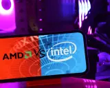 Telefon z logo AMD vs Intel na tle podświetlanego komputera.