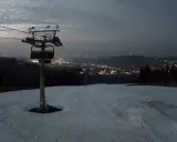 Widok z bukowina ski kamery na ośnieżony stok i nocne światła miasta w oddali.