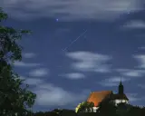 Ein Sternschnuppenregen über einer kleinen Kirche. Man sieht, wann sieht man sternschnuppen, wenn der Himmel klar ist und die Nacht dunkel.