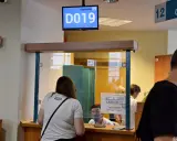 Kobieta czeka na odbiór dowodu rejestracyjnego. Na ekranie wyświetla się numer stanowiska D019.