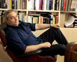 L'autore, circondato da libri, si rilassa su una poltrona. Tra i titoli, si intravede un riferimento a de Giovanni ultimo libro.