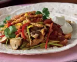 En läcker portion fajitas kyckling med paprika, champinjoner och gräddfil på en tortilla.