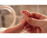 Un piedino di neonato tenuto da una mano adulta. Un'immagine che evoca la delicatezza e l'importanza della valutazione Apgar, un test per valutare le condizioni del neonato alla nascita.