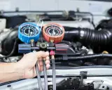 Mechanik sprawdza ciśnienie w układzie klimatyzacji, przygotowując nowy czynnik klimatyzacji do napełnienia.