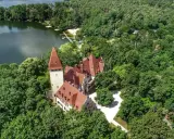 Zamek w Lubniewicach, otoczony bujną zielenią, malowniczo położony nad jeziorem.
