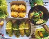 Involtini di verza pronti per essere cotti, alcuni impanati, altri legati con filo, con patate e peperoncini intorno.