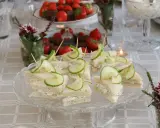 Smörgåsar med gurka och krämig fyllning, perfekta för ett afternoon tea recept. Jordgubbar och choklad i bakgrunden.