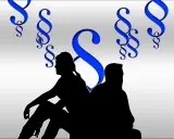 Sylwetki pary siedzą plecami do siebie, otoczone symbolami paragrafu, co sugeruje trudny podział majątku po rozwodzie.